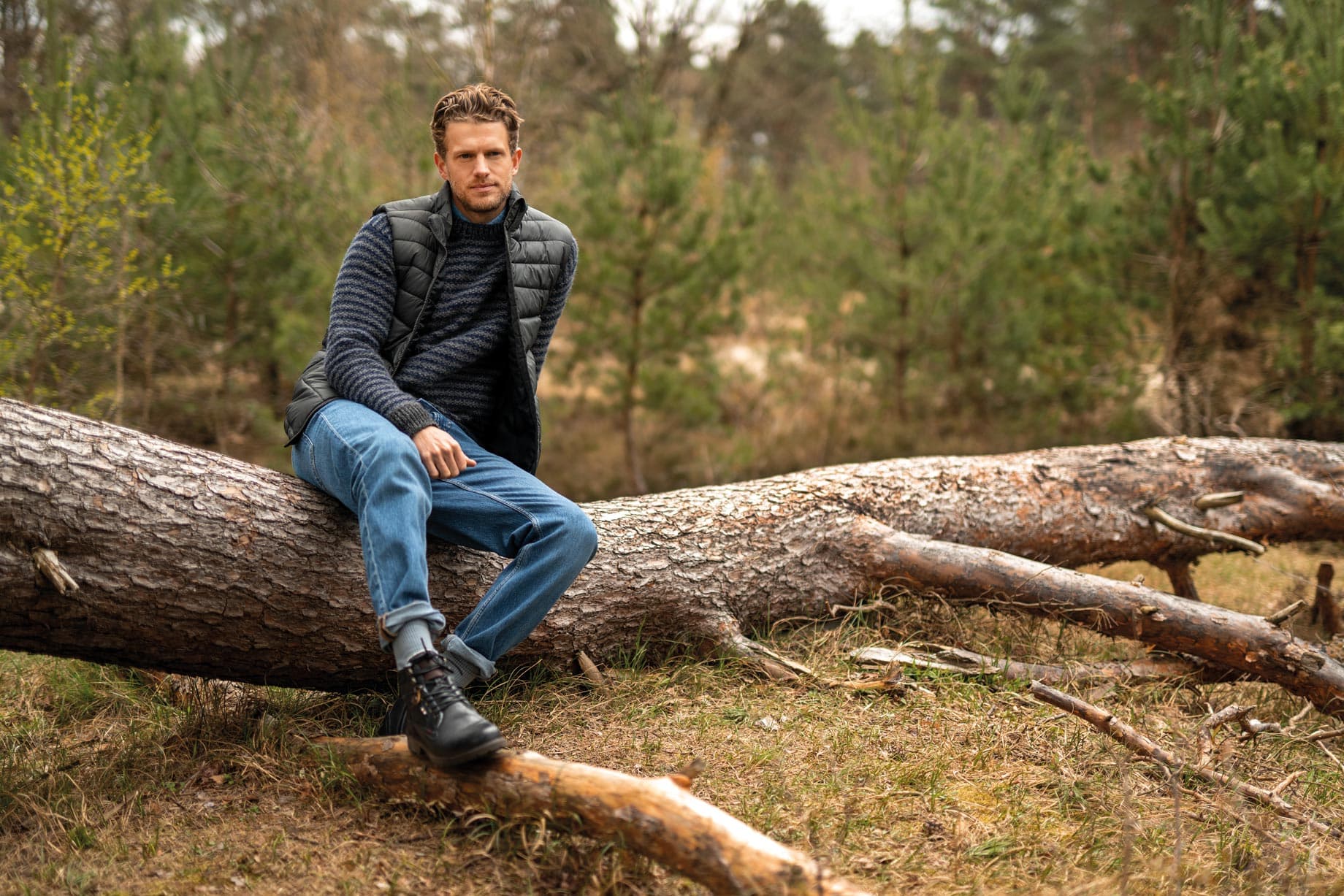 Mann mit blauen Boots sitzt im Herbst im Wald